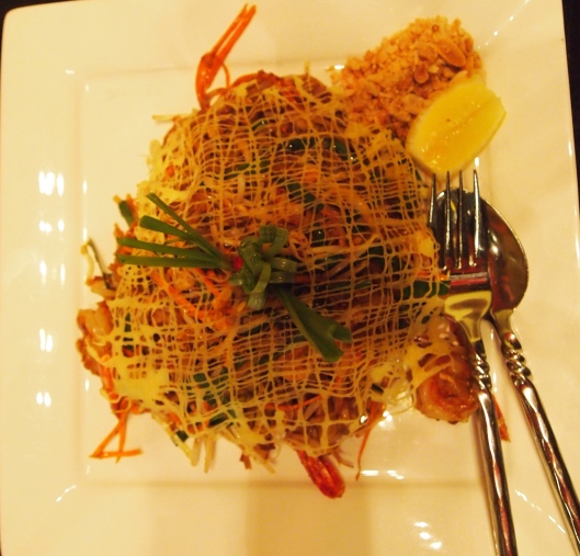 Pad Thai with Prawns with eggs drizzled and cooked on top in an artistic pattern